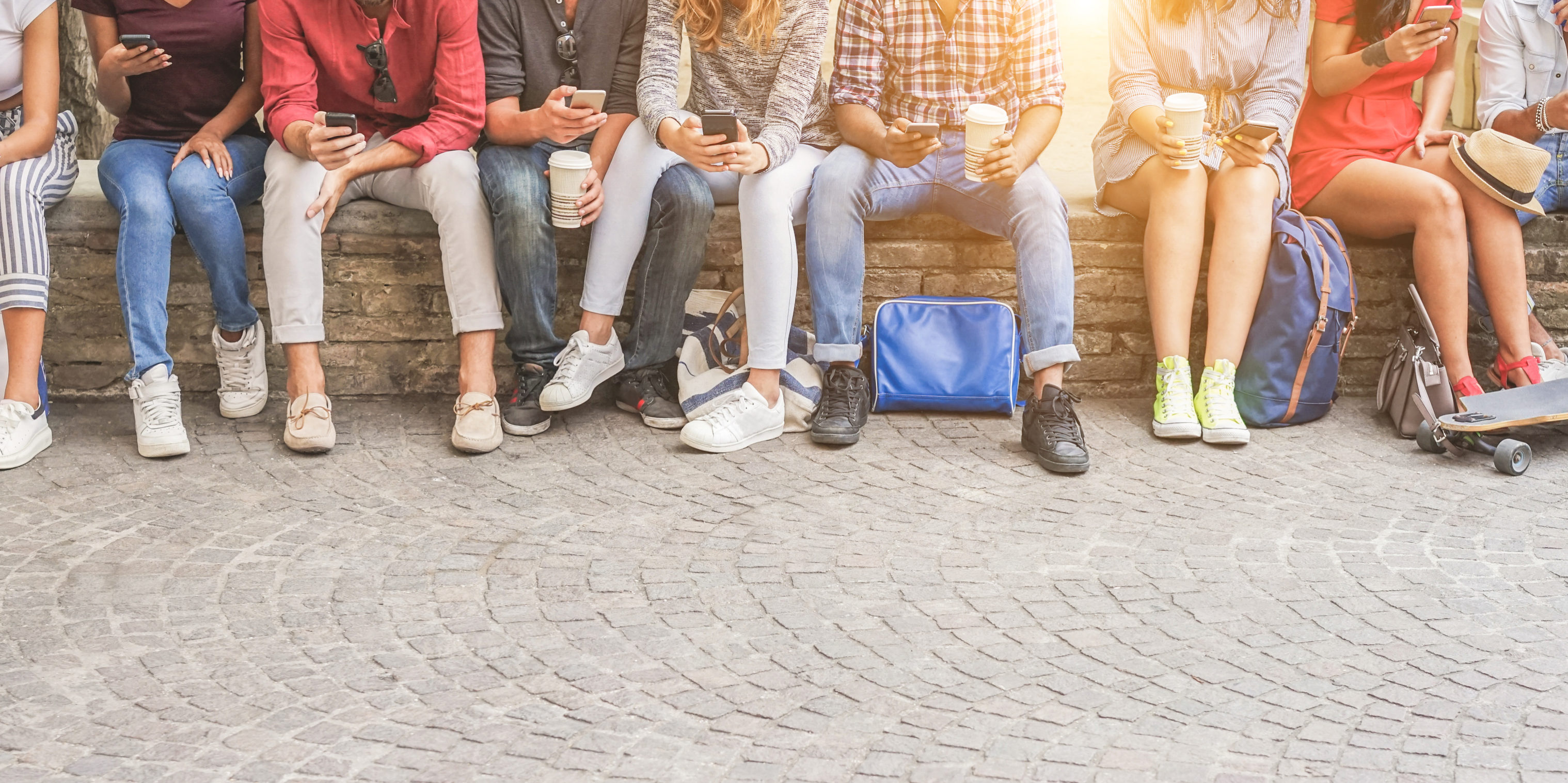 Young friends using smartphones and drinking coffee