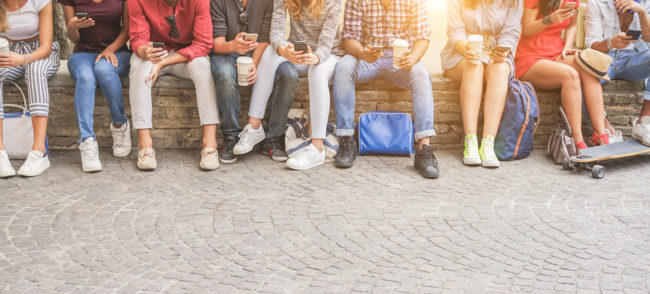 Young friends using smartphones and drinking coffee outdoor – Group of people having fun with technology trends – Youth, new generation addiction and friendship concept – Main focus on center guys Young friends using smartphones and drinking coffee
