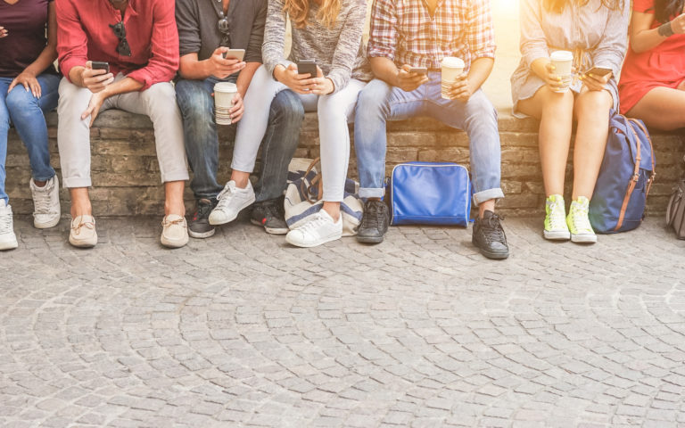 Young friends using smartphones and drinking coffee outdoor – Group of people having fun with technology trends – Youth, new generation addiction and friendship concept – Main focus on center guys Young friends using smartphones and drinking coffee