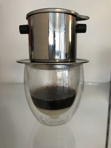 Der Ca phe sua: heißer Kaffee tropft aus dem Filter (Phin) in ein mit Kondensmilch gefülltes Glas