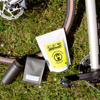 Zwei Kaffees und Thermobecher drapiert auf Fahrradreifen