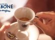 Person hält weiße Espressotasse gefüllt mit Kaffee in der Hand
