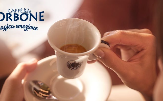 Person hält weiße Espressotasse gefüllt mit Kaffee in der Hand