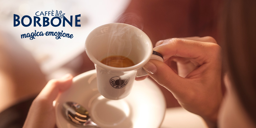 Person hält weiße Espressotasse gefüllt mit Kaffee in der Hand