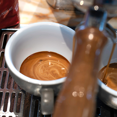 Essse Selezione Speciale Crema Espresso fließt aus dem Siebträger. Marmorierte Crema sammelt sich am Boden der Espressotasse