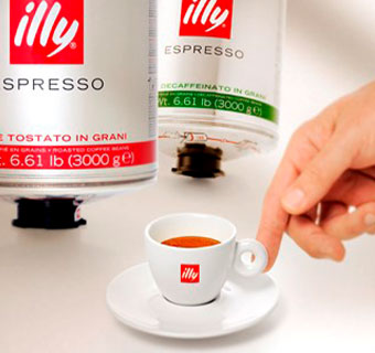 Eine Hand greift zur weißen illy Espressotasse, daneben stehen zwei  illy Espressosorten