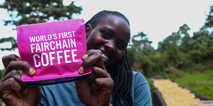 Frau hält glücklich die pinke Kaffeeverpackung von Moyee Coffee in den Händen