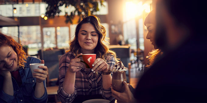 Drei Frauen sitzen im Wiener Kaffeehaus  un d trinken aus roten Julius Meinl Tassen