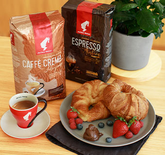 Zwei Julius Meinl Caffè Crema mit einem Croissant Frühstücksteller und einer roten Espressotasse